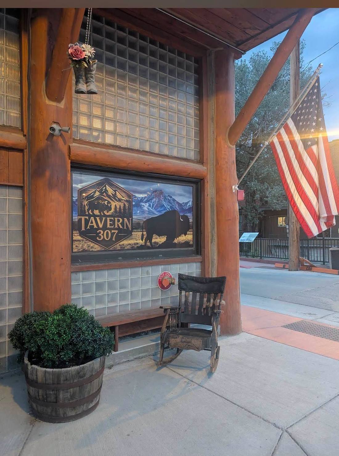 Tavern 307 storefront on Main Street at dusk with the flag out front