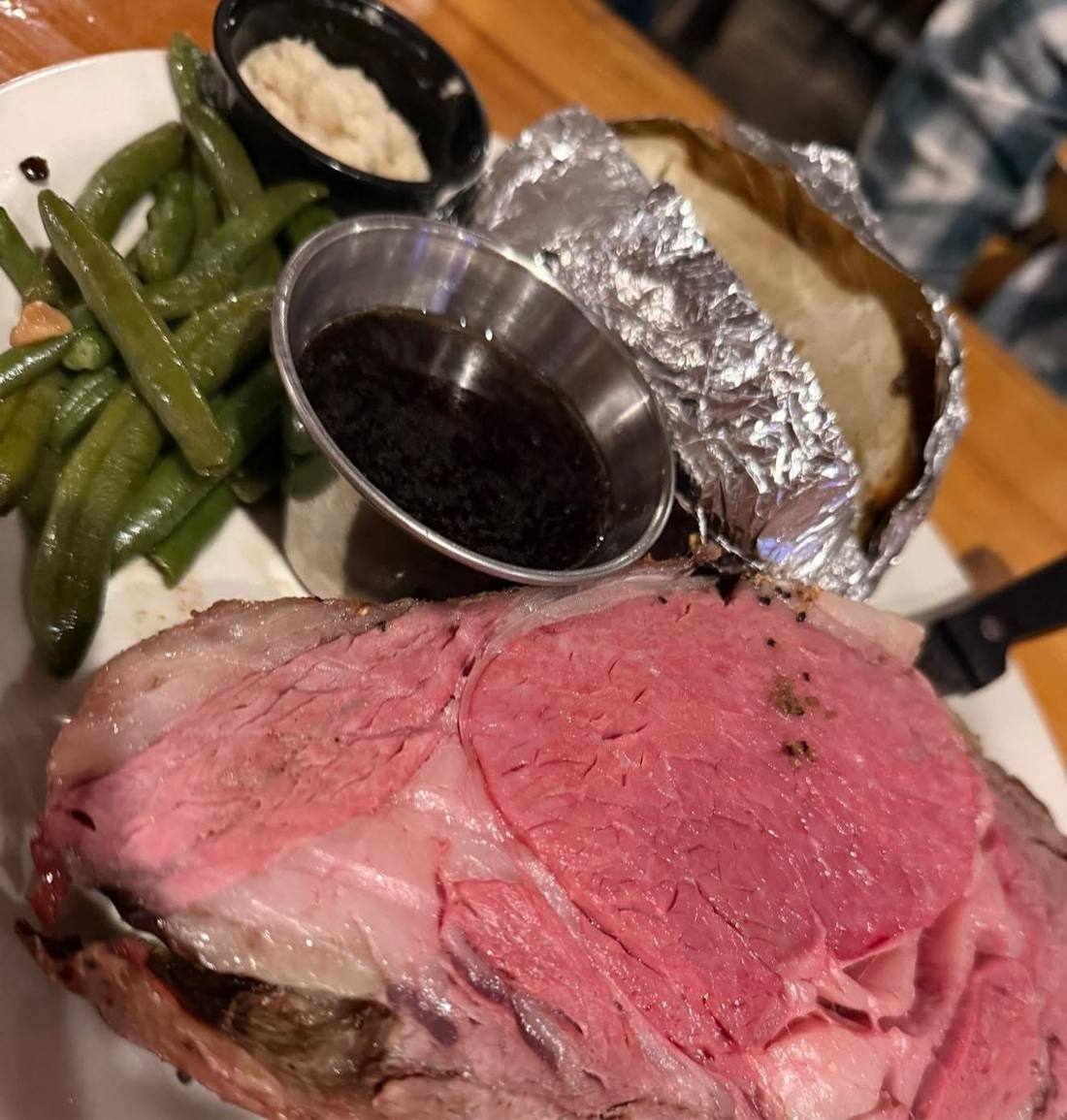 Prime rib dinner with au jus, baked potato, and green beans