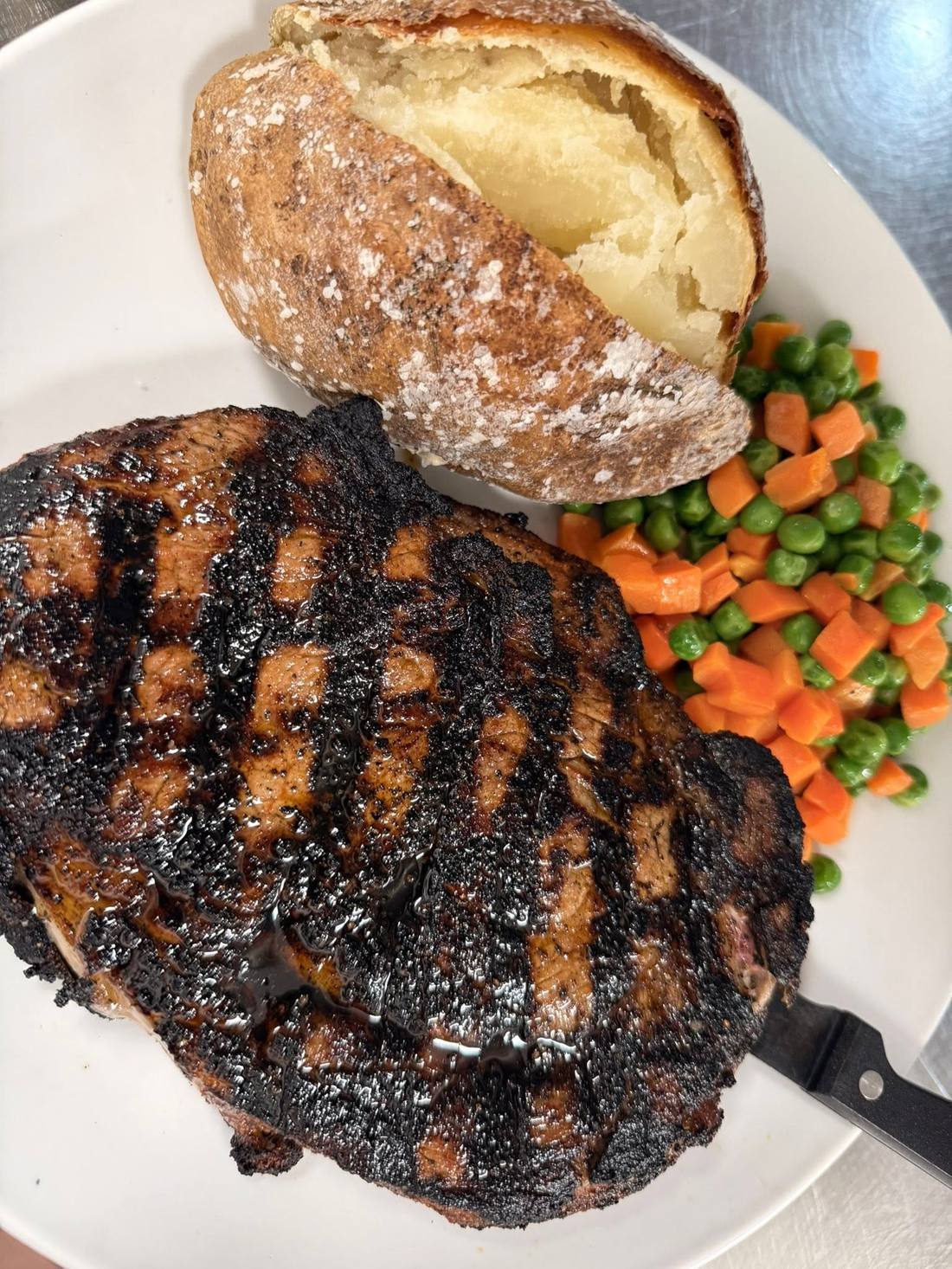 Char-grilled steak with a baked potato and vegetables